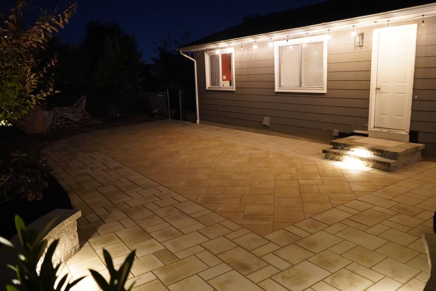 Paver patio with landscape lighting at night