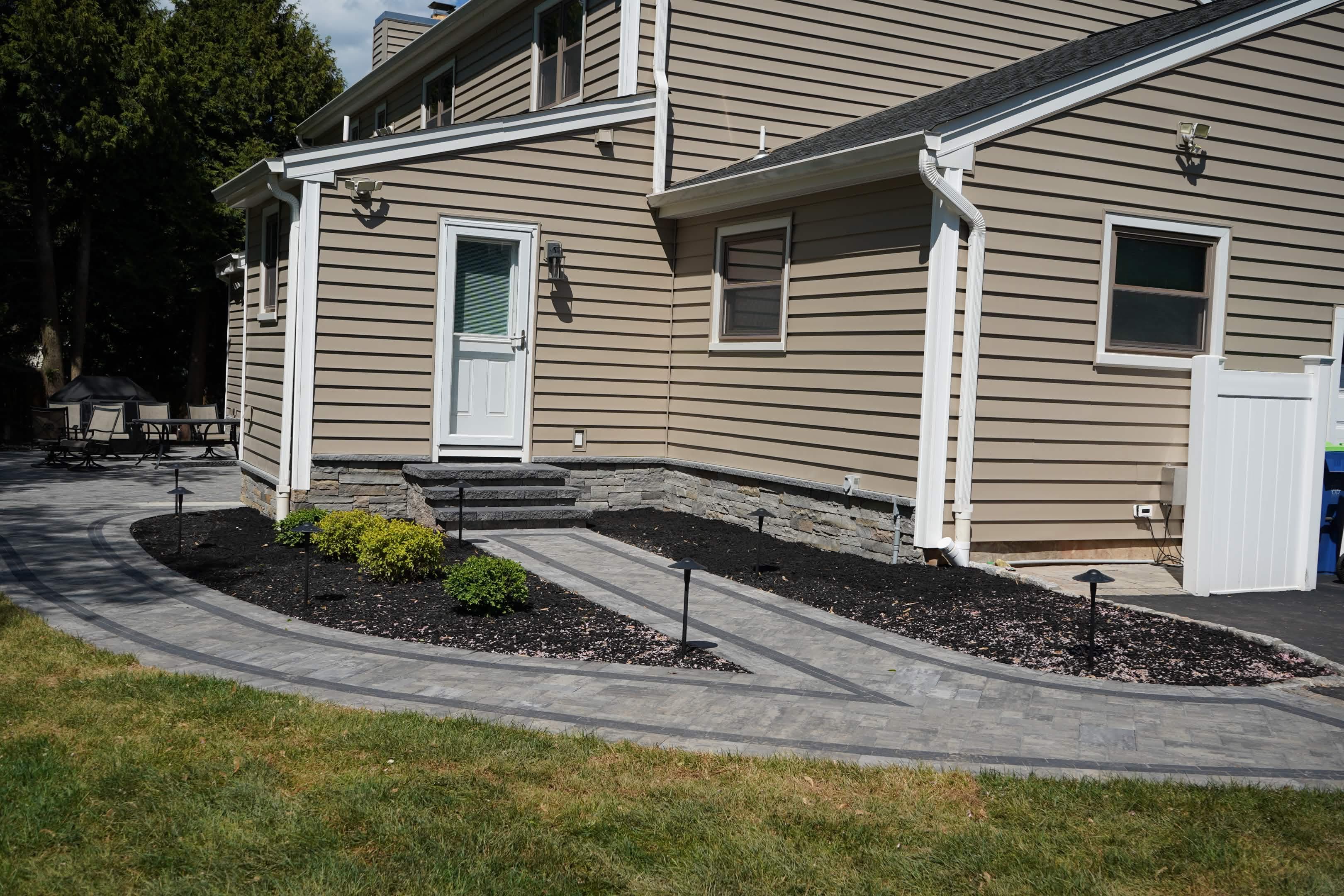 Finished paver walkway with planting beds and landscape lighting