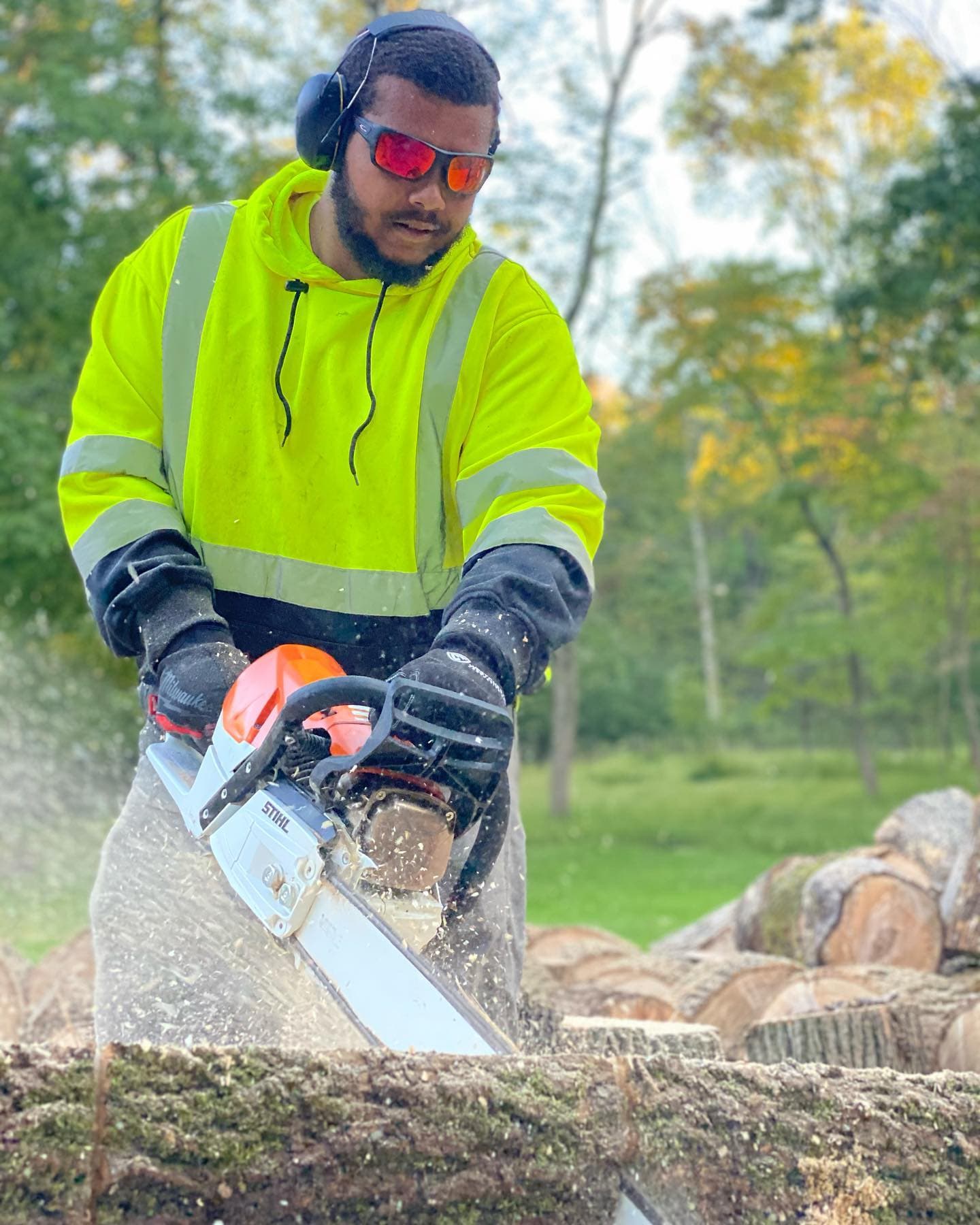 Sultan Services crew member cutting tree with chainsaw during cleanup