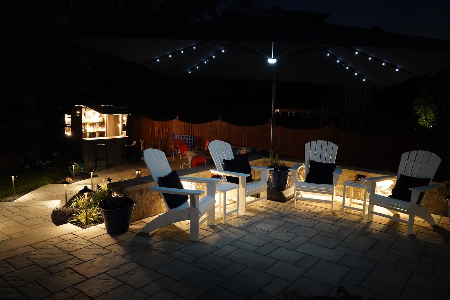 Outdoor living patio with landscape lighting at night