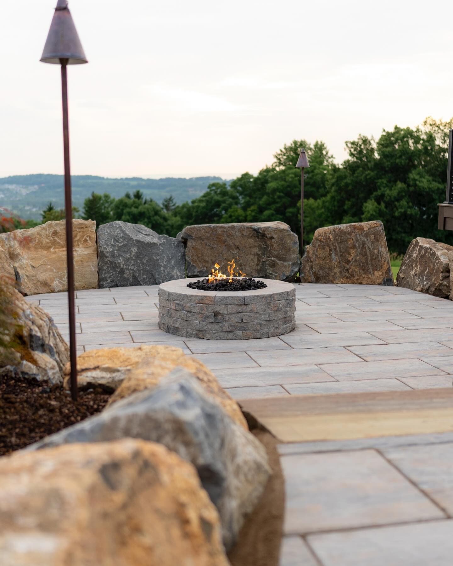 Paver fire pit patio with boulder seating and hilltop view
