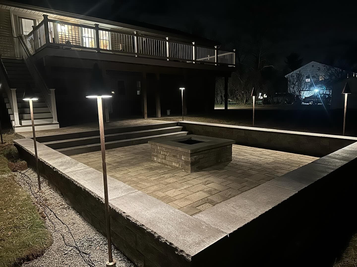 Patio with fire pit and landscape lighting at night