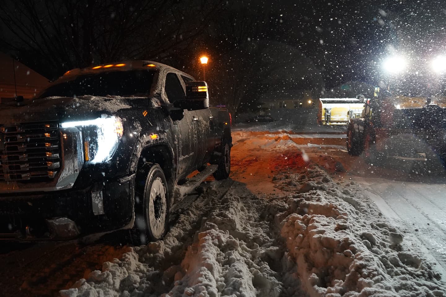 Sultan Services plow truck and loader working during nighttime storm